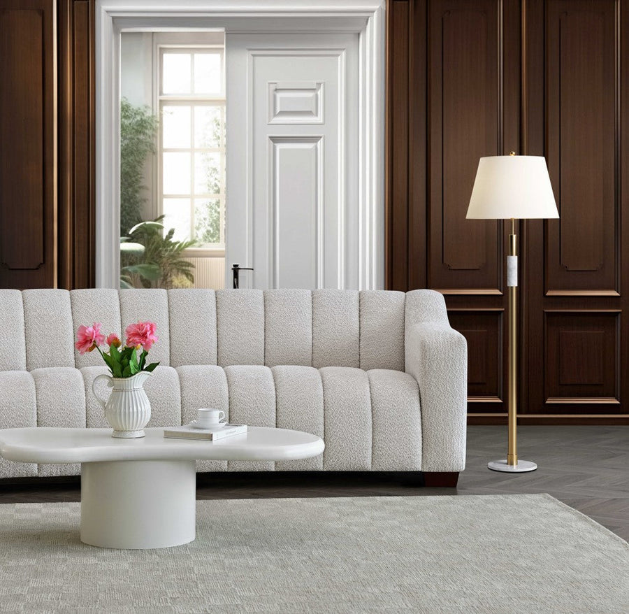 White boucle channel back sofa in a living room with a coffee table and floor lamp
