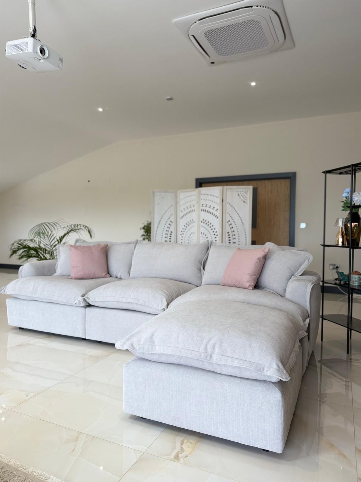Modern light grey fabric sectional sofa with pink cushions in a bright contemporary living room
