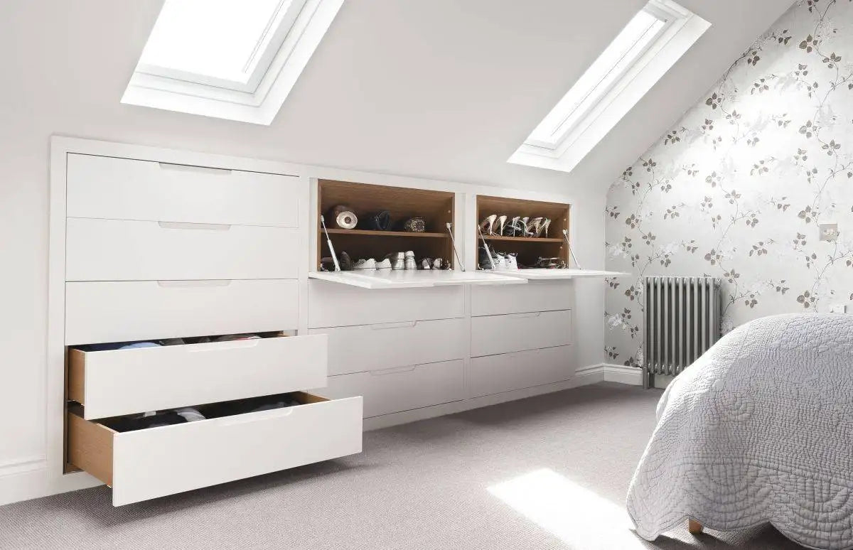 Custom white built-in attic wardrobe storage with drawers and shelving under sloped ceilings