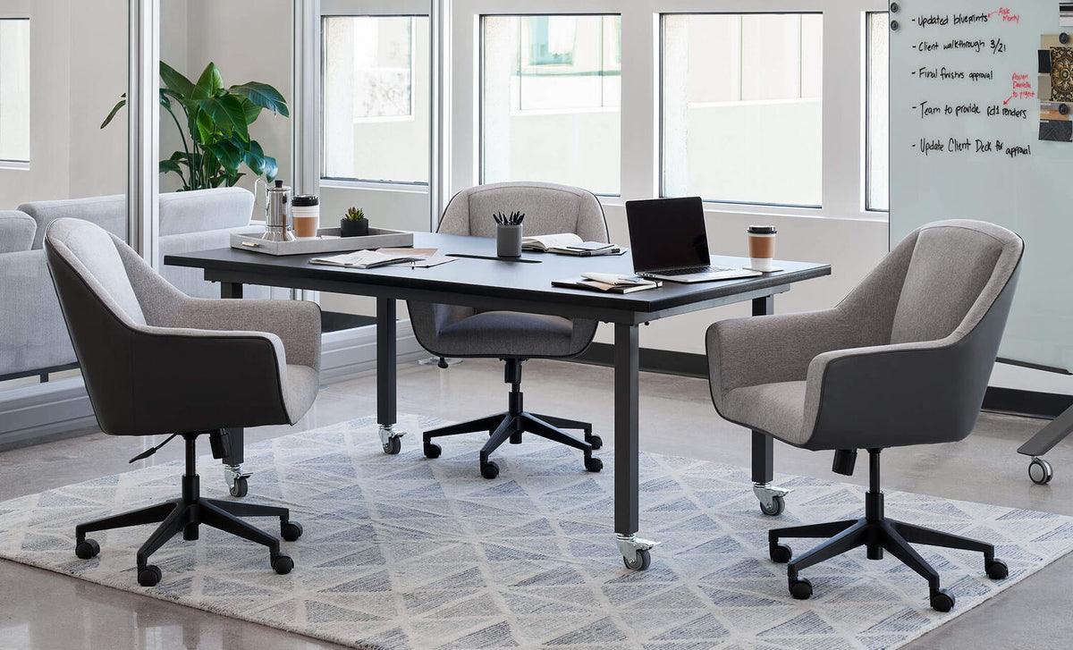 Modern grey office meeting room chairs around a black conference table in a bright office setting.