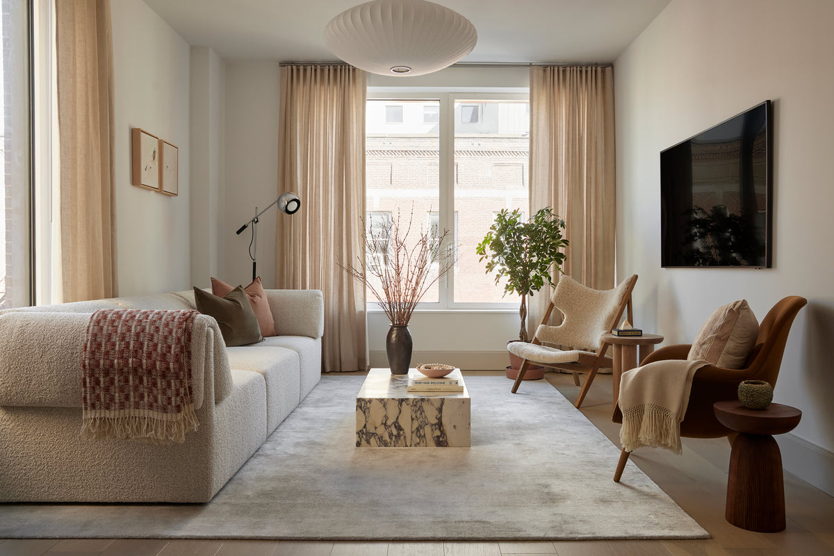 Modern living room featuring a white boucle sofa, marble coffee table, and neutral decor.